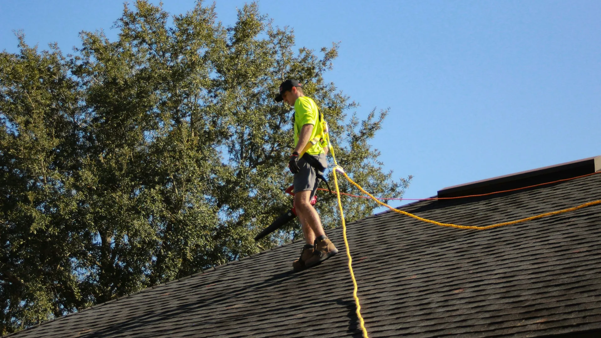 Roofer working on an asphalt shingle roof under a clear sky