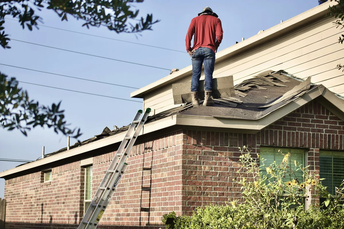 Roofer standing on the roof of a brick home during a roof inspection