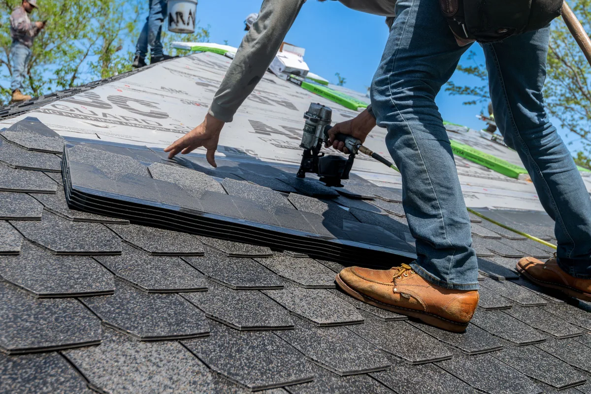 Roofer nailing architectural asphalt shingles