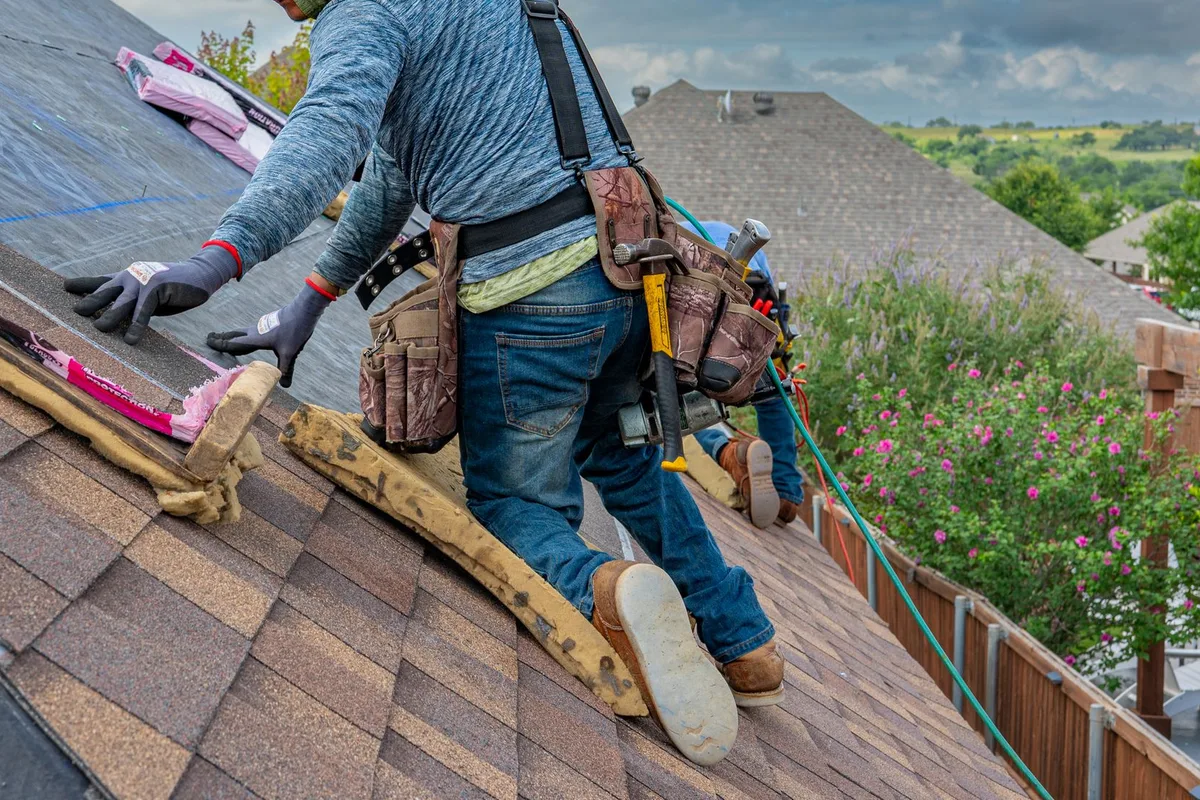 Roofer laying new asphalt shingles